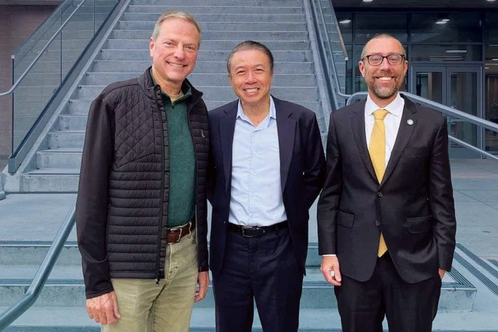 Three men standing side by side on outdoor steps at the engineering school, all facing the camera.